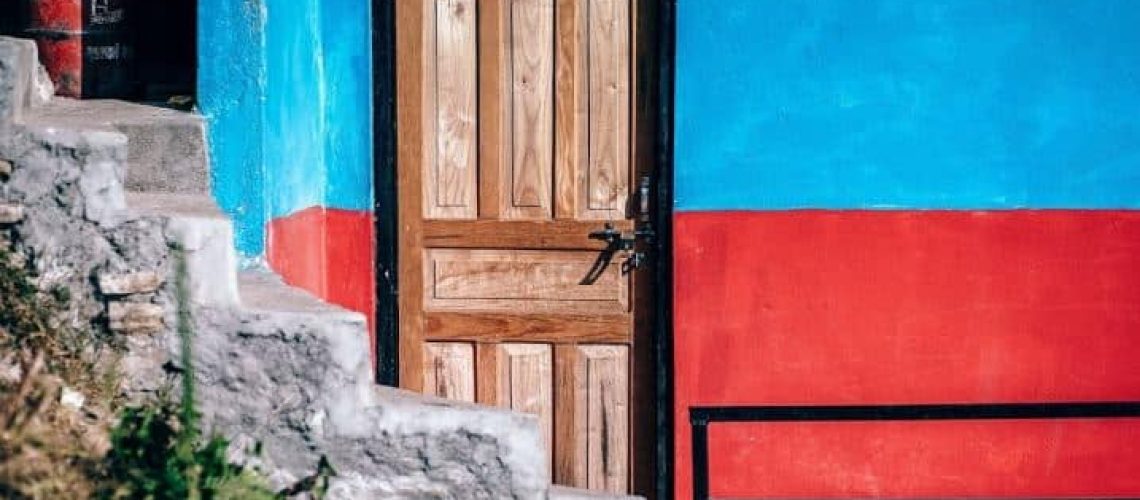 Bright red door on blue building depicting most important things a resume can not do for you